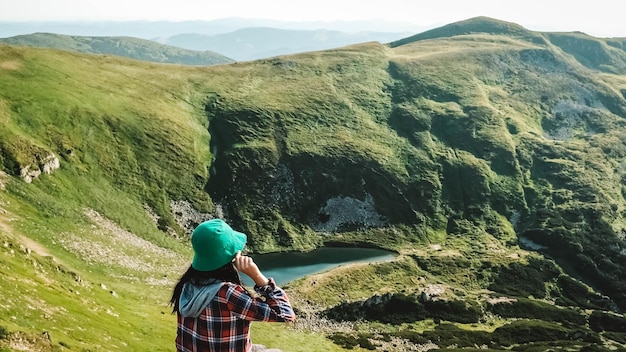 Turista de mulher no fundo das montanhas verdes e lago