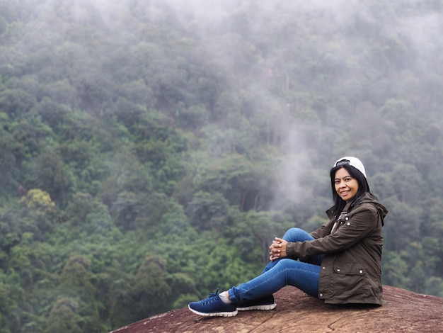 Turista de mulher sorridente feliz sentado sobre a floresta tropical verde