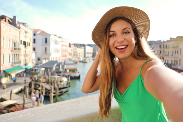 Foto turista de veneza na ponte rialto tirando uma foto de selfie com o famoso grande canal ao fundo