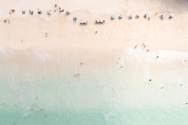 Turista de vista aérea superior brincando no mar de férias e guarda-chuva no conceito de férias de verão de praia