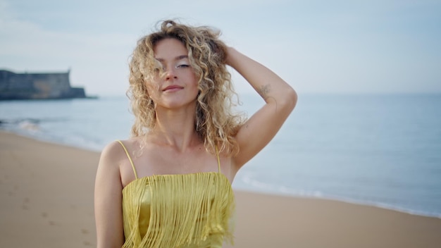 Turista despreocupado caminando por la playa mirando a la cámara con una sonrisa suave de cerca