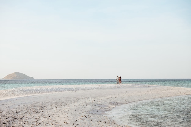 Turista de dos mujeres caminando en la playa de arena blanca