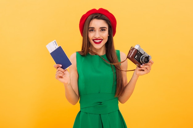 Turista emocionado de la mujer joven que sostiene la cámara y el pasaporte con los boletos.