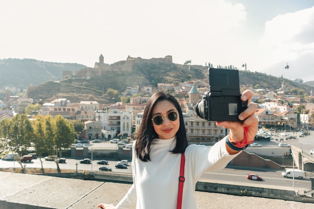 Turista está tomando selfie de sí misma y la vista del casco antiguo de Tbilisi en Georgia.