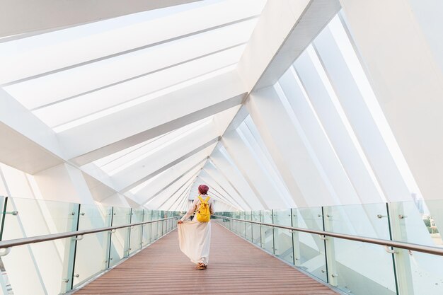 Turista feliz andando e admirando o interior único da ponte pedonal sobre o canal de água em Dubai Emirados Árabes Unidos