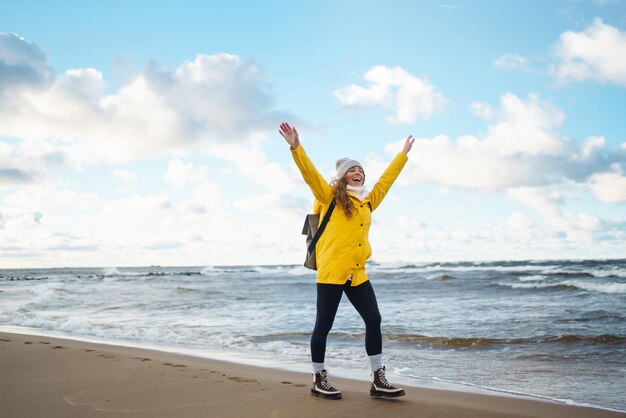 Turista feliz con una chaqueta amarilla disfrutando del paisaje marítimo al atardecer Aventura de estilo de vida de viaje