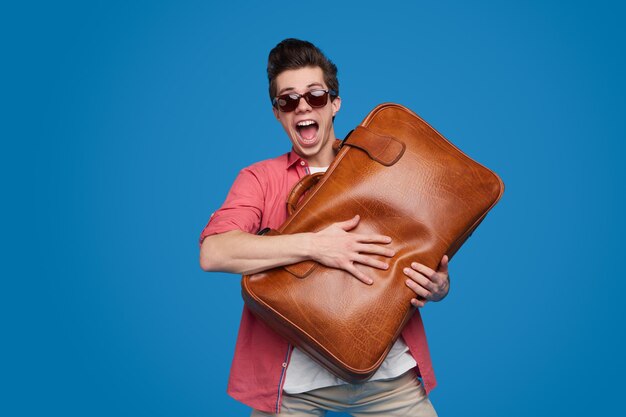 Turista feliz con maleta de cuero en estudio