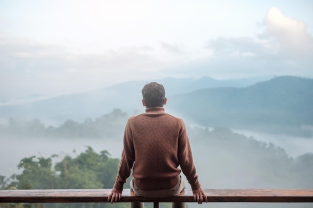 Un turista feliz relajándose y mirando la vista de la montaña en casa de campo o en casa de familia por la mañana. Vacaciones, blogger, SoloTravel, viaje, viaje y concepto relajante