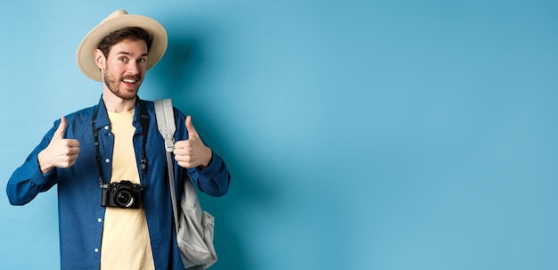 Foto un turista feliz y sonriente dice que sí y muestra su aprobación yendo de vacaciones de verano con una mochila y una foto