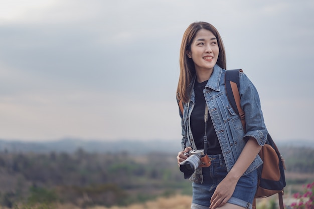 Foto turista femenina con mochila y cámara en campo