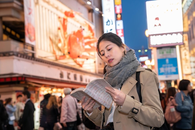 turista feminina elegante está indo para o próximo local para ver a visão noturna de seu mapa depois do jantar