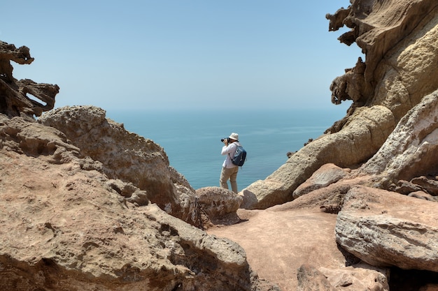 Turista fotografiando la naturaleza, de pie en el borde del acantilado., Isla iraní de Ormuz, Hormozgan, Irán.