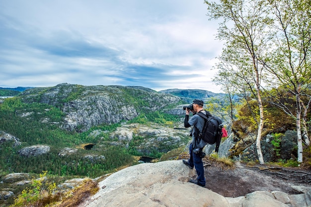 Turista fotógrafo de la naturaleza con tomas de cámara mientras está de pie en la cima de la montaña. Hermosa Naturaleza Noruega.