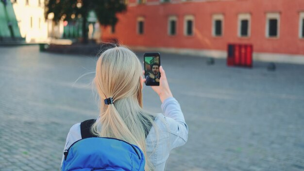 Turista haciendo videollamadas en el teléfono inteligente con su amiga de otro lugar