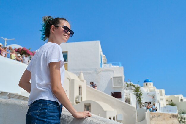 Turista hermosa chica feliz en la isla de Santorini en Grecia, adolescente femenina viajando a través del Mediterráneo. Arquitectura famosa isla blanca y fondo de cielo azul, espacio de copia