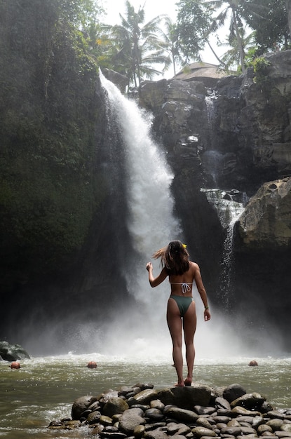 Turista hermoso joven que visita la cascada de Tegenungan en Bali