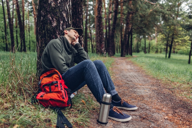 Turista hombre cansado durmiendo en el bosque de la primavera. El viajero se detuvo para descansar. Concepto de camping, viaje y deporte.