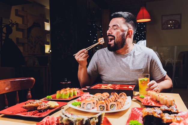 Foto turista homem comendo comida asiática rua café local, sorria usando o pauzinho.