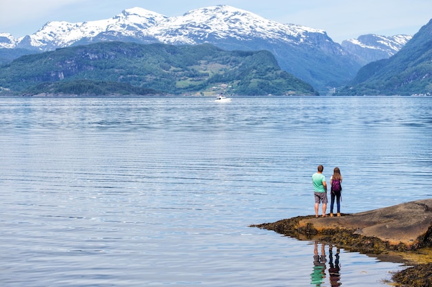 Turista homem e menina com uma mochila em pé na costa Hardangerfjorden, Noruega