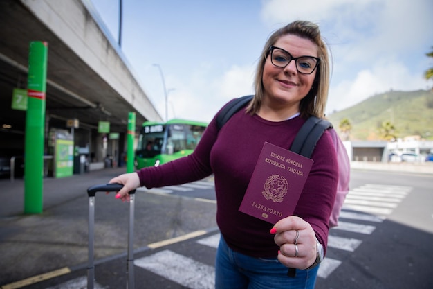 Foto una turista italiana tiene su pasaporte en la mano mientras está de pie en la estación de autobuses.