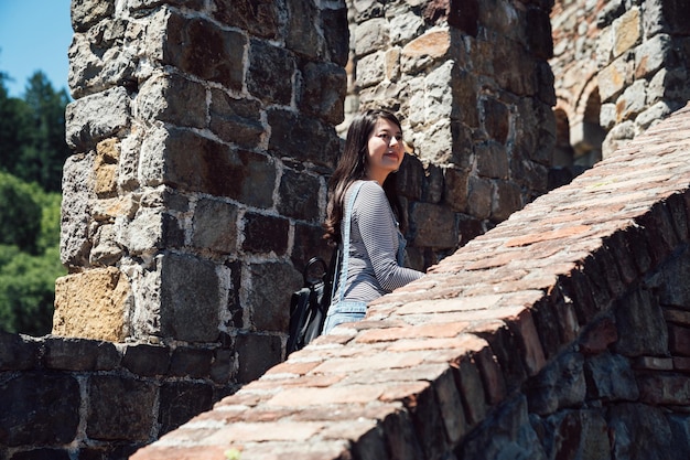 Turista jovem desfrutando de bela vista aérea sobre a cidade velha na Europa. viajante de menina asiática visitando o antigo castelo medieval subindo as escadas feliz sorrindo. história de experiência do estudante universitário.