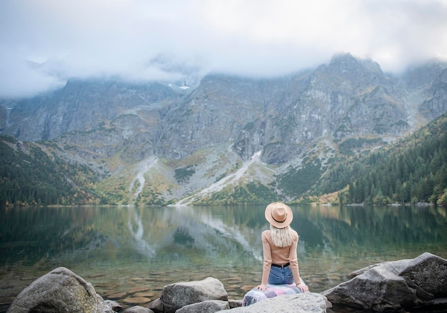 Turista jovem sentada no pico da montanha e belas montanhas