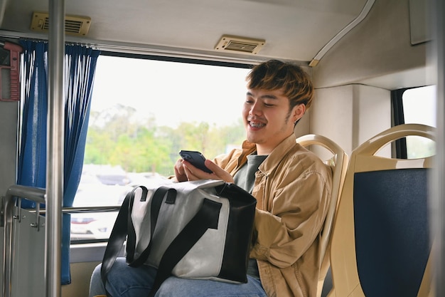 Turista joven feliz usando un teléfono inteligente en el transporte público Gente y concepto de transporte