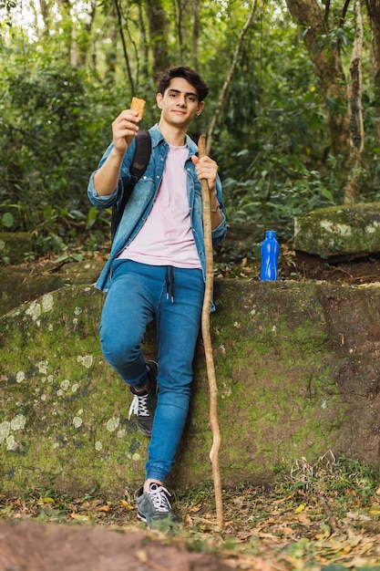 Turista joven hermoso que disfruta de su descanso mientras come una barra de cereal.