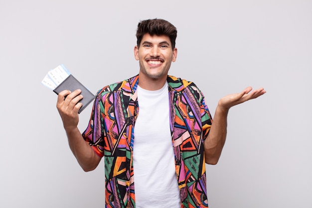 Turista joven con pasaporte que se siente feliz, emocionado, sorprendido o conmocionado, sonriendo y asombrado por algo increíble