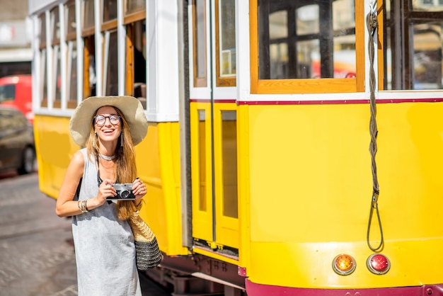 Turista joven de pie cerca del famoso tranvía amarillo retro que viaja en la ciudad de Lisboa, Portugal.