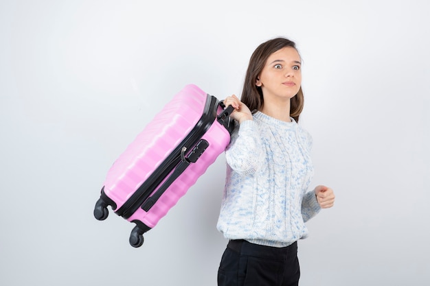 Foto turista joven viajero con maleta rosa esperando destino.