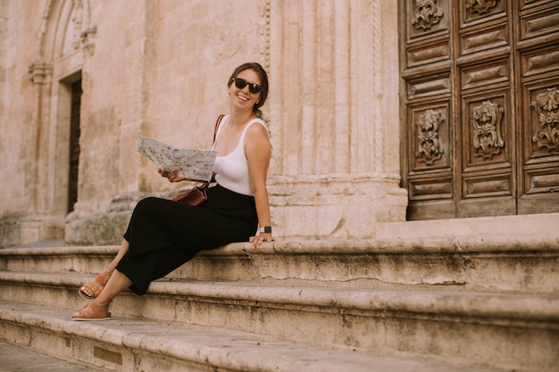 Turista con un mapa de la ciudad junto a la iglesia de San Francesco d'Assisi en Ostuni, Italia