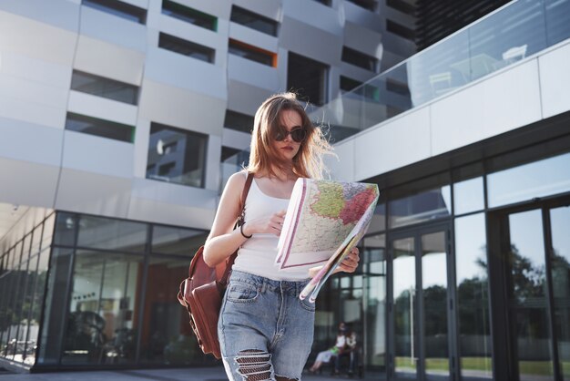 Turista con mapa visitando una nueva ciudad y está buscando un camino hacia el hotel