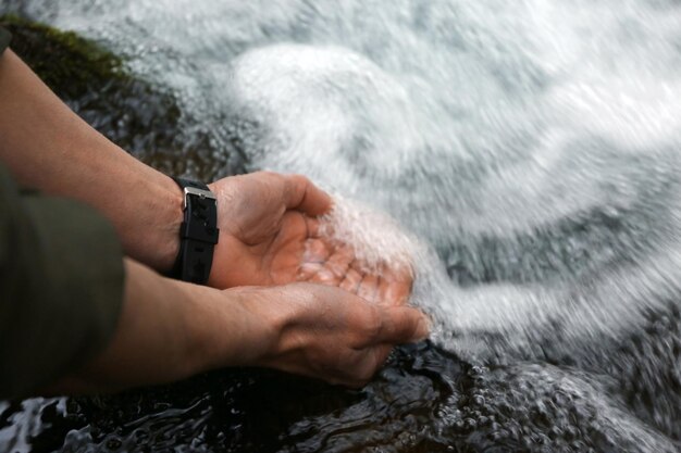 Turista masculino bebiendo agua del río