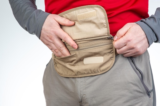 Turista masculino com uma bolsa de cintura para coisas e documentos em uma bolsa de cinto de viagem com um zíper para coisas e documento enquanto viaja