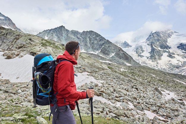 Turista masculino escalando acantilados rocosos nevados de los hermosos Alpes Penning en Suiza