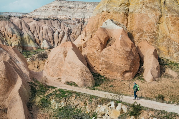 Turista masculino explorando los valles rojo y rosa de Capadocia. Montañas de arenisca mágica y paisajes de cuevas cerca de Goreme.