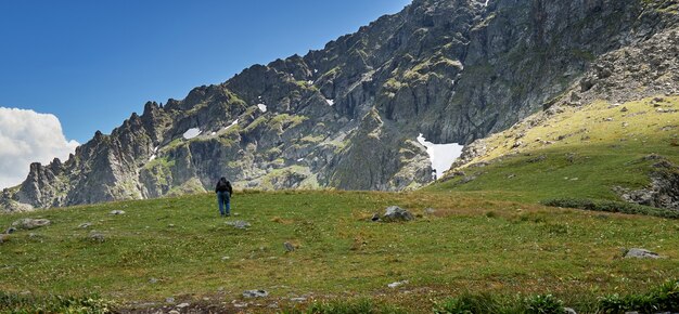 Turista masculino con mochila sube a la cima de la montaña. Altai