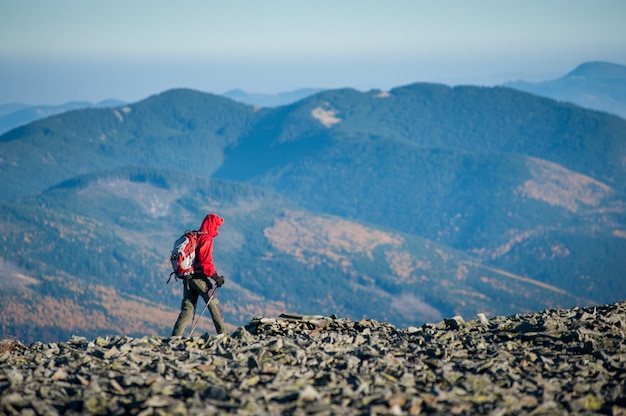 Turista masculino que camina en el canto de la montaña rocosa con las montañas hermosas en fondo