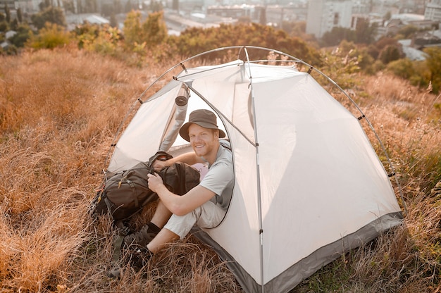 Un turista masculino sentado cerca de la carpa y con aspecto pacífico.