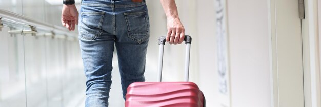 Foto turista masculino tira maleta mudándose a hotel de lujo