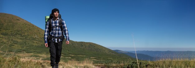 Turista masculino vestido con una camisa lleva una mochila grande