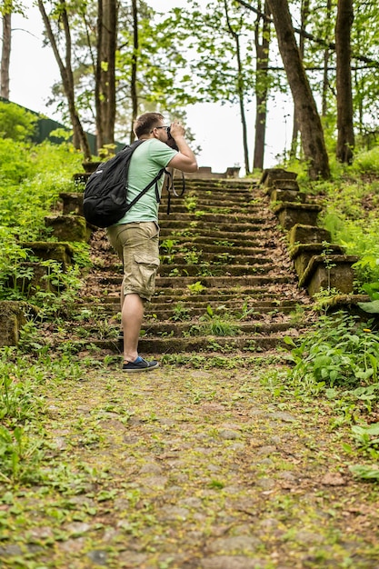 Turista con mochila hace fotos de bosque de verano en el parque