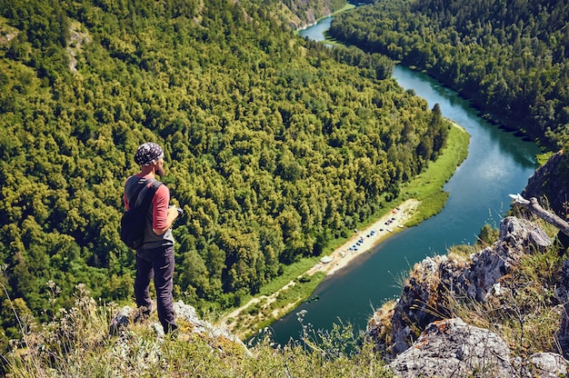 Un turista con una mochila en una roca disfrutando de una vista del valle del río