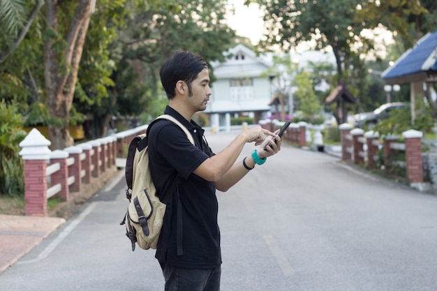 El turista con la mochila utilizó el teléfono móvil en el concepto del camino, del viaje y del estilo de vida