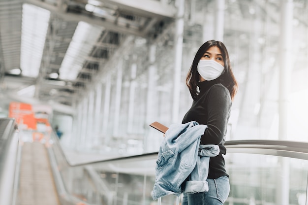 Turista mujer asiática vistiendo mascarilla con pasaporte