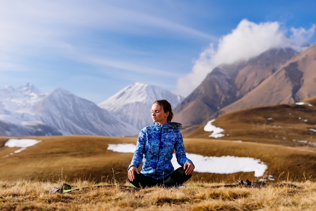 Turista de mujer se sienta en el fondo de las montañas y practicando yoga