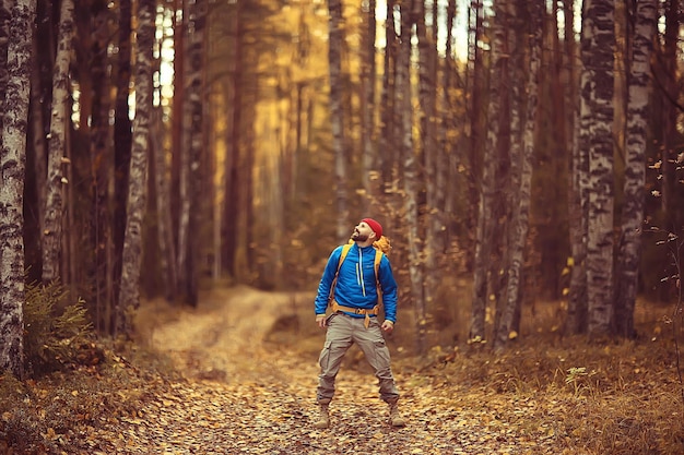 turista na floresta de outono em uma estrada florestal, uma aventura na floresta de outubro, um homem caminhando paisagem de outono
