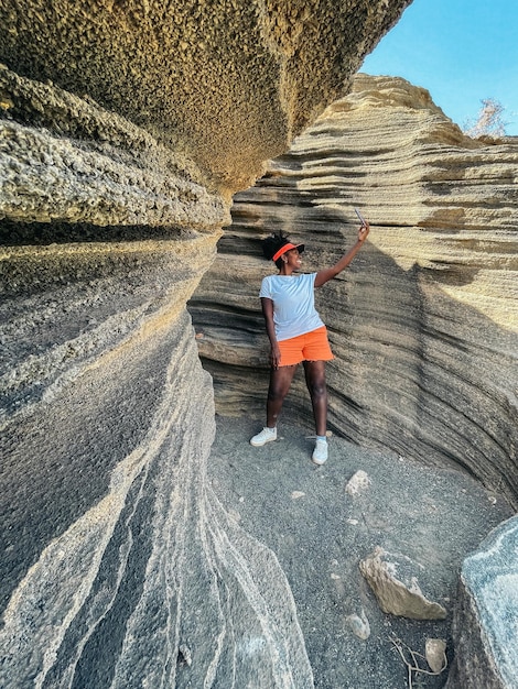 Foto turista negro tomando selfie en barranco en verano