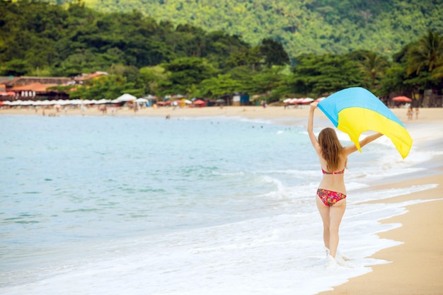 Turista de niña con una bandera de Ucrania en la playa de Río de Janeiro, Brasil